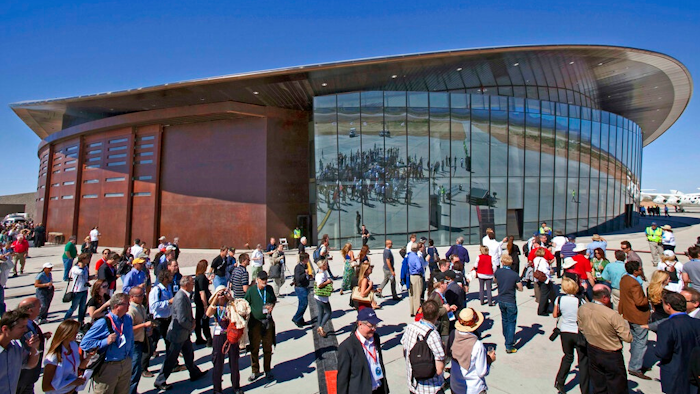 In this Oct. 17, 2011 file photo, guests stand outside the new Spaceport America hangar in Upham, N.M. Virgin Galactic is scheduled to unveil the interior of its digs at Spaceport America, providing the first glimpse of mission control, a prep area for pilots and where paying customers will lounge ahead of their suborbital flights. Company officials are gathering Thursday, Aug. 15, 2019, at the remote facility in the New Mexico desert to show off two levels of the custom-tailored hangar at the taxpayer-financed spaceport.