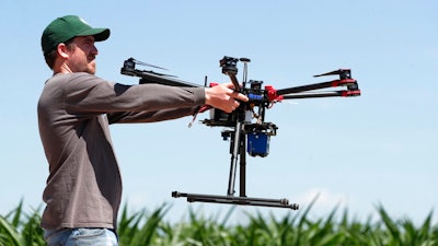 In this Thursday, July 11, 2019, photograph, United States Department of Agriculture intern Alex Olsen prepares to place down a drone at a research farm northeast of Greeley, Colo. Researchers are using drones carrying imaging cameras over the fields in conjunction with stationary sensors connected to the internet to chart the growth of crops in an effort to integrate new technology into the age-old skill of farming.