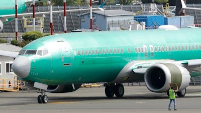 In this May 8, 2019, file photo a worker stands near a Boeing 737 MAX 8 jetliner being built for American Airlines prior to a test flight in Renton, Wash. Boeing is working on new software for the 737 Max that will use a second flight control computer to make the system more reliable, solving a problem that surfaced in June with the grounded jet, two people briefed on the matter said Friday, Aug. 2.