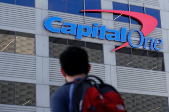 In this July 16, 2019, file photo, a man walks across the street from a Capital One location in San Francisco. Federal prosecutors say Paige Thompson, the woman accused of hacking Capital One and at least 30 other organizations, is a threat to herself and society, a flight risk and should be kept locked up until her trial. Prosecutors are expected to make their argument for detaining Thompson at a hearing Friday, Aug. 23 in Seattle. Prosecutors say the former software engineer has a history of stalking and threatening to kill people and to get herself killed by police. Her lawyers denied that she is violent.