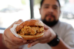 Randy Estrada holds up his chicken sandwich at a Popeyes in Kyle, Texas. After Popeyes added a crispy chicken sandwich to their fast-fast menu, the hierarchy of chicken sandwiches in America was rattled, and the supremacy of Chick-fil-A and others was threatened.