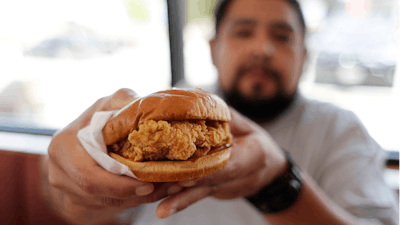 Randy Estrada holds up his chicken sandwich at a Popeyes in Kyle, Texas. After Popeyes added a crispy chicken sandwich to their fast-fast menu, the hierarchy of chicken sandwiches in America was rattled, and the supremacy of Chick-fil-A and others was threatened.