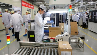 In this March 6, 2019, file photo a staff member works on a mobile phone production line during a media tour in Huawei factory in Dongguan, China's Guangdong province. Huawei Technologies Co. is one of the world's biggest supplier of telecommunications equipment. The United States is delaying tariffs on Chinese-made cellphones, laptop computers and other items and removing other Chinese imports from its target list altogether in a move that triggered a rally on Wall Street.