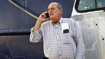 In this Oct. 14, 2014, file photo, Carlos Rafael talks on the phone at Homer's Wharf near his herring boat F/V Voyager in New Bedford, Mass. Rafael was sentenced to prison in 2017 after pleading guilty to evading fishing quotas and smuggling profits overseas. The federal government announced Monday, Aug. 19, 2019, it has settled its civil case against Rafael, a fishing magnate known as The Codfather, saying he will never be allowed to return to U.S. fisheries.