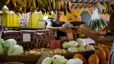 Olga Castillo counts the change after selling vegetables to a customer at her stall in Havana, Cuba, Wednesday, July 30, 2019. The Cuban government is capping prices for food and beverages throughout the country in order to control the risk of inflation due to a state wage hike and stagnant productivity.