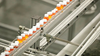 In this July 10, 2018, file photo bottles of medicine ride on a belt at a mail-in pharmacy warehouse in Florence, N.J. Drug companies are still raising prices for brand-name prescription medicines, just not as often or by as much as they used to, according to an Associated Press analysis.