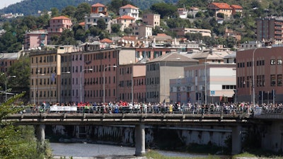 People that did not take part in the ceremony to mark the first anniversary of the Morandi bridge collapse, stage their own commemoration on the bridge on the Polcevera river in Genoa, Italy, Wednesday, Aug. 14, 2019. The Morandi bridge was a road viaduct on the A10 motorway in Genoa, that collapsed one year ago killing 43 people.