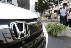 In this July 31, 2019, photo, people walk past a Honda car on display at Honda Motor Co. headquarters in Tokyo. Japanese automaker Honda reported Friday, Aug. 2, a 29% decline in fiscal first quarter profit as an unfavorable currency exchange and declining auto sales in the U.S. and India hurt earnings.