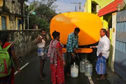 In this Tuesday, July 16, 2019, photo, people fill drinking water from a private water supplier tanker on the outskirts of Chennai, capital of the southern Indian state of Tamil Nadu. In Chennai, a coastal city of about 10 million and the capital of Tamil Nadu state, rapid development and rampant construction have overtaxed a once-abundant natural water supply, forcing the government to spend huge sums to desalinate sea water, bring water by train from hundreds of kilometers (miles) away and deploy an army of water trucks to people whose household taps have suddenly run dry.
