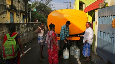 In this Tuesday, July 16, 2019, photo, people fill drinking water from a private water supplier tanker on the outskirts of Chennai, capital of the southern Indian state of Tamil Nadu. In Chennai, a coastal city of about 10 million and the capital of Tamil Nadu state, rapid development and rampant construction have overtaxed a once-abundant natural water supply, forcing the government to spend huge sums to desalinate sea water, bring water by train from hundreds of kilometers (miles) away and deploy an army of water trucks to people whose household taps have suddenly run dry.