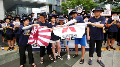 South Korean college students tear banners showing an image of a Japanese rising sun flag and the logo of Mitsubishi Corp. during a rally to denounce Japan's new trade restrictions on South Korea in front of the office of Mitsubishi Corp. in Seoul, South Korea, Wednesday, Aug. 7, 2019. Japanese Prime Minister Shinzo Abe said Tuesday that the main cause of escalating tensions between Japan and South Korea is a loss of trust over court rulings ordering Japanese companies to compensate South Koreans for forced labor during World War II.