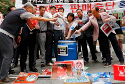 In this July 15 2019, photo, South Korean small and medium-sized business owners pour beers and drinking waters from Japanese brands into a trash can during a rally calling for a boycott of Japanese products in front of the Japanese embassy in Seoul, South Korea, The signs read: 'Our supermarket does not sell Japanese products.' A widespread anti-Japanese boycott has gained ground in South Korea since Tokyo tightened its exports of materials used to manufacture semiconductors and display screens, key export items for South Korea.