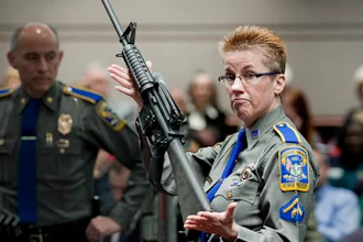 In this Jan. 28, 2013, file photo, firearms training unit Detective Barbara J. Mattson, of the Connecticut State Police, holds up a Bushmaster AR-15 rifle, the same make and model of gun used by Adam Lanza in the December 2012 Sandy Hook School shooting, during a hearing of a legislative subcommittee in Hartford, Conn. Gunmaker Remington Arms filed a request on Thursday, Aug. 1, 2019, asking the U.S. Supreme Court to hear its appeal of a Connecticut court ruling that reinstated a wrongful death lawsuit against the company. Remington cited a 2005 federal law that shields gunmakers in most cases from liability when their products are used in crimes.