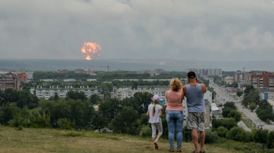A family watches explosions at a military ammunition depot near the city of Achinsk in eastern Siberia's Krasnoyarsk region.