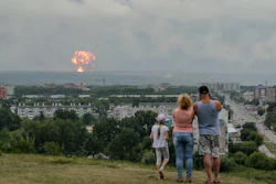 In this photo taken on Monday, August 5, 2019, a family watches explosions at a military ammunition depot near the city of Achinsk in eastern Siberia's Krasnoyarsk region.