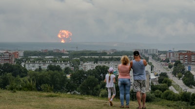 In this photo taken on Monday, August 5, 2019, a family watches explosions at a military ammunition depot near the city of Achinsk in eastern Siberia's Krasnoyarsk region.