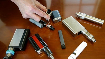 In this Tuesday, April 10, 2018 photo, Marshfield High School Principal Robert Keuther displays vaping devices that were confiscated from students in such places as restrooms or hallways at the school in Marshfield, Mass. Illinois health officials are reporting what could be United States' first death tied to vaping. In a Friday, Aug. 23, 2019, news release, the Illinois Department of Public Health says a person who recently vaped died after being hospitalized with 'severe respiratory illness.' The agency didn't give any other information about the patient, including a name or where the person lived.