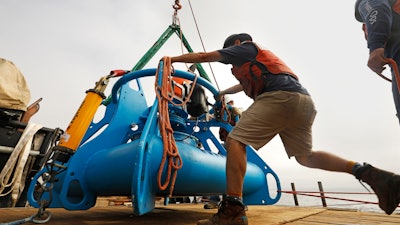Jeff Pietro, a senior engineer assistant for Woods Hole Oceanographic Institute in Massachusetts, helps move the anchoring system for a microphone, at it is being lowered over the side of the ship in the Santa Barbara Channel off Southern California.