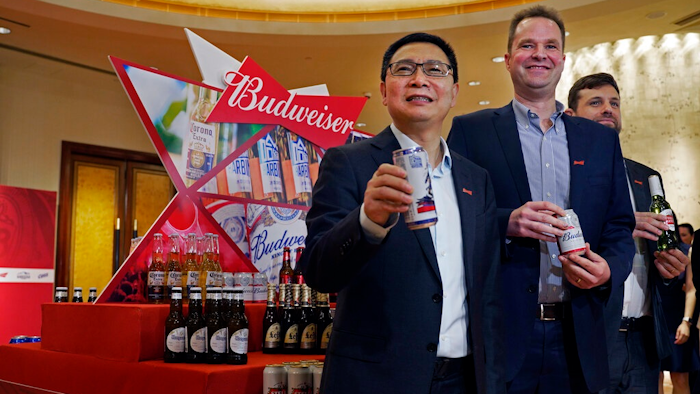 From left, Frank Wang, Executive Director, Jan Craps, Executive Director and CEO and Guilherme Castellan, Chief Financial Officer of Budweiser Brewing Company APAC Limited pose with products in Hong Kong Tuesday, Sept. 17, 2019. AB InBev, the world's largest brewer that produces Budweiser and Corona, has revived plans to list its Asian business in Hong Kong despite persistent pro-democracy protests but halved the size of its initial public offering.