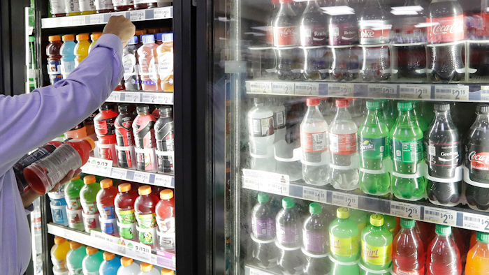 In this Monday, Oct. 1, 2018 file photo, a shop owner reaches into a drink display refrigerator at his convenience store in Kent, Wash. A study on America’s eating habits released on Tuesday, Sept. 24, 2019 shows only slight improvement from 1999 to 2016. While adults cut down a bit on added sugars and ate marginally more whole grains, they still eat too many sweetened foods and unhealthy fats.