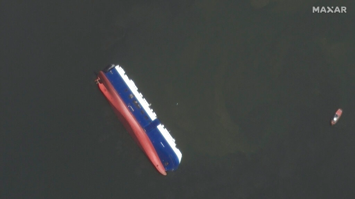 This Sept. 10, 2019 satellite photo provided by Maxar Technologies, shows the capsized cargo shop Golden Ray in Jekyll Island, Ga. A fire broke out aboard the ship early Sunday, listing it to the side and blocking the shipping channel. The Coast Guard and a salvage crew freed the four remaining Golden Ray crew members.