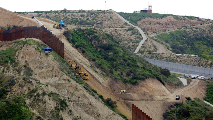 In this March 11, 2019 photo, construction crews replace a section of the primary wall separating San Diego, above right, and Tijuana, Mexico, below left, seen from Tijuana, Mexico. Defense Secretary Mark Esper has approved the use of $3.6 billion in funding from military construction projects to build 175 miles of President Donald Trump’s wall along the Mexican border.