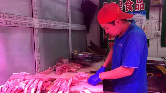 A butcher slices cuts of pork at a meat market in Beijing.
