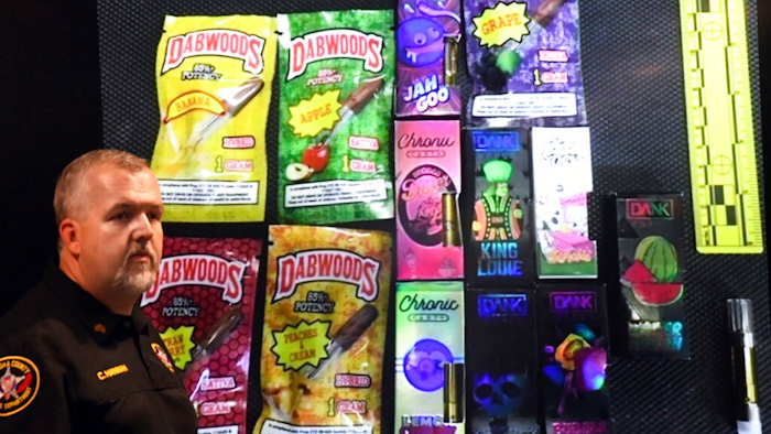 Sgt. Christopher Hannah of the Kenosha County Sheriff's Department stands in front of a display of the colorfully packaged vaping products during a news conference in Kenosha Wednesday, Sept. 11, 2019.