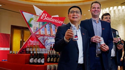 From left, Frank Wang, Executive Director, Jan Craps, Executive Director and CEO and Guilherme Castellan, Chief Financial Officer of Budweiser Brewing Company APAC Limited pose with products in Hong Kong Tuesday, Sept. 17, 2019. AB InBev, the world's largest brewer that produces Budweiser and Corona, has revived plans to list its Asian business in Hong Kong despite persistent pro-democracy protests but halved the size of its initial public offering.