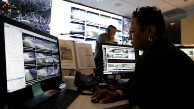 In this photo, Sandra Swint, right, campus security associate for Fulton County School District and Paul Hildreth, background, the district’s emergency operations coordinator, work in the emergency operations center at the Fulton County Schools Administration Center in Atlanta. Artificial Intelligence is transforming surveillance cameras from passive sentries into active observers that can immediately spot a gunman, alert retailers when someone is shoplifting and help police quickly find suspects. Schools, such as the Fulton County School District, are among the most enthusiastic adopters of the technology.