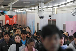 In this file photo commuters walk by surveillance cameras installed at a walkway in between two subway stations in Beijing.