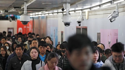 In this file photo commuters walk by surveillance cameras installed at a walkway in between two subway stations in Beijing.