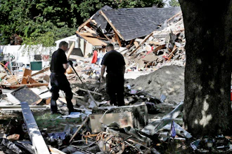 In this Sep. 21, 2018, file photo, fire investigators pause while searching the debris at a home which exploded following a gas line failure in Lawrence, Mass. Federal officials are discussing their findings from a yearlong investigation into last September's natural gas explosions and fires in Massachusetts. The National Transportation Safety Board meets in Washington, D.C., on Tuesday, Sept. 24, 2019, to discuss and vote on its final report about the Sept. 13, 2018, incident.