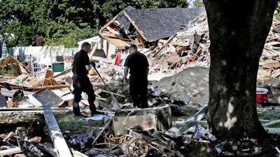 In this Sep. 21, 2018, file photo, fire investigators pause while searching the debris at a home which exploded following a gas line failure in Lawrence, Mass. Federal officials are discussing their findings from a yearlong investigation into last September's natural gas explosions and fires in Massachusetts. The National Transportation Safety Board meets in Washington, D.C., on Tuesday, Sept. 24, 2019, to discuss and vote on its final report about the Sept. 13, 2018, incident.