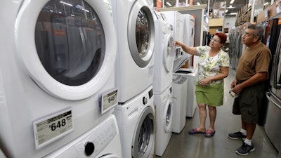In this Monday, Sept. 23 photo, Maria Alvarez, left, and her husband Guillermo Alvarez, right, both of Boston, examine clothes washers and dryers at a Home Depot store location, in Boston.