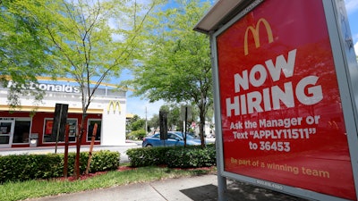 In this Monday, July 1, 2019, file photo, a 'Now Hiring' sign appears on a bus stop in front of a McDonald's restaurant in Miami. Starting Wednesday, Sept. 25, 2019, McDonald’s Corp. will let job seekers start an application by using voice commands on their smartphones with Amazon’s Alexa or Google’s Assistant.