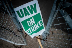 In this Monday, Sept. 16, 2019, file photo, a United Auto Workers strike sign rests between the chains of a locked gate entrance outside of Flint Engine Operations in Flint, Mich. As the United Auto Workers’ strike against General Motors continues, consumers, the company and striking workers are starting to get pinched.