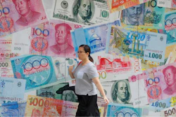In this Aug. 6, 2019, file photo, a woman walks by a money exchange shop decorated with different countries currency banknotes at Central, a business district in Hong Kong. China has urged President Donald Trump to oppose bullying following the American leader’s criticism of its trade status in a speech at the United Nations. A foreign ministry spokesman on Wednesday, Sept. 25, called on Trump to “meet China halfway” in settling trade disputes.