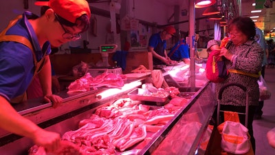 In this Wednesday, Sept. 11, 2019, file photo, a clerk stacks cuts of pork at a meat market in Beijing. China is releasing pork from stockpiles for the second time this month to help cool surging prices ahead of next week’s celebration of the Communist Party's 70th anniversary in power.