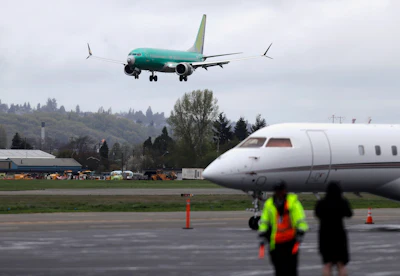 In this April 10, 2019, file photo a Boeing 737 MAX 8 airplane being built for India-based Jet Airways, top, lands following a test flight at Boeing Field in Seattle.