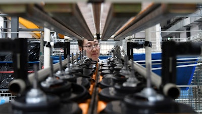 In this May 15, 2019, file photo, a factory worker checks parts at a manufacturing plant for automobile air conditioners in Yantai in eastern China's Shandong province.
