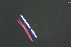 This Sept. 10, 2019 satellite photo provided by Maxar Technologies, shows the capsized cargo shop Golden Ray in Jekyll Island, Ga. A fire broke out aboard the ship early Sunday, listing it to the side and blocking the shipping channel. The Coast Guard and a salvage crew freed the four remaining Golden Ray crew members.