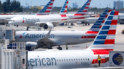 In this April 24, 2019, photo, American Airlines aircraft are shown parked at their gates at Miami International Airport in Miami. An American Airlines mechanic is accused of sabotaging a flight from Miami International Airport to Nassau in the Bahamas, over stalled union contract negotiations. Citing a criminal complaint affidavit filed in federal court, The Miami Herald reports Abdul-Majeed Marouf Ahmed Alani was arrested Thursday, Sept. 5, 2019, on the sabotage charge and is accused of disabling the flight's navigation system.