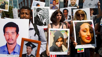 Beza Alemu, left, from Ethiopia, along with other demonstrators, holds pictures of his brother Mulusew Alemu, who died in the plane crash, during a vigil on the six-month anniversary of the crash of a Boeing 737 Max 8, killing 157 people, in Ethiopia on March 10, which has resulted in the grounding hundreds of the planes worldwide, outside of the Department of Transportation, Tuesday, Sept. 10, 2019 in Washington.