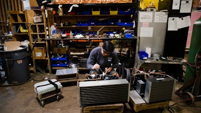In this Oct. 18, 2018, file photo Minh Pham works on a compressor unit at a commercial refrigeration manufacturing facility in Philadelphia. Small manufacturers and retailers are losing confidence in the national economy yet remain upbeat about their own prospects. That’s the finding of a third quarter survey of 1,000 companies released last week by the U.S. Chamber of Commerce and MetLife.
