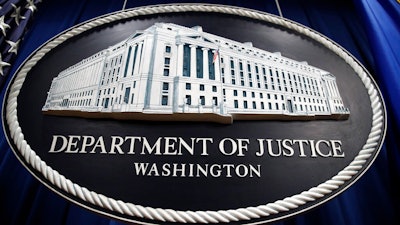 In this Thursday, April 18, 2019, file photo, a sign for the Department of Justice hangs in the press briefing room at the Justice Department, in Washington. The U.S. Justice Department is conducting an antitrust investigation of four automakers that have signed on with California in a deal to toughen tailpipe emissions standards. In July, Ford, Honda, Volkswagen and BMW reached a deal with California to abide by standards that are tougher than those preferred by the Trump administration. The standards are closely linked with fuel economy requirements.