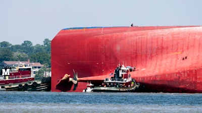 Rescuers work near the stern of the vessel Golden Ray as it lays on its side near the Moran tug boat Dorothy Moran, Monday, Sept. 9, 2019, in Jekyll Island, Ga. Coast Guard rescuers have made contact with four South Korean crew members trapped inside the massive cargo ship off the coast of Georgia.