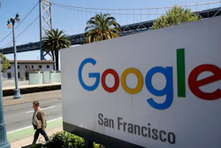 In this May 1, 2019, file photo a man walks past a Google sign outside with a span of the Bay Bridge at rear in San Francisco. A group of states are expected to announce an investigation into Google on Monday, Sept. 9, to investigate whether the tech company has become too big.