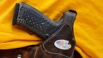 In this April 14, 2018 file photo, a man wears an unloaded pistol during a pro gun-rights rally in Austin, Texas. In a letter sent to the Senate on Thursday, Sept. 12, 2019, CEOs from businesses including Airbnb, Twitter and Uber asked Congress to pass a bill to require background checks on all gun sales and a strong red flag law that would allow courts to issue life-saving extreme risk protection orders.