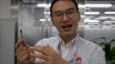 In this Aug. 21, 2019, photo, a Huawei research engineer holds up a coated screw designed to reduce signal interference at the Huawei Materials lab in Dongguan in Southern China's Guangdong province. Facing a ban on access to U.S. technology, Chinese telecom equipment maker Huawei is showing it increasingly can do without American components and compete with Western industry leaders in pioneering research.